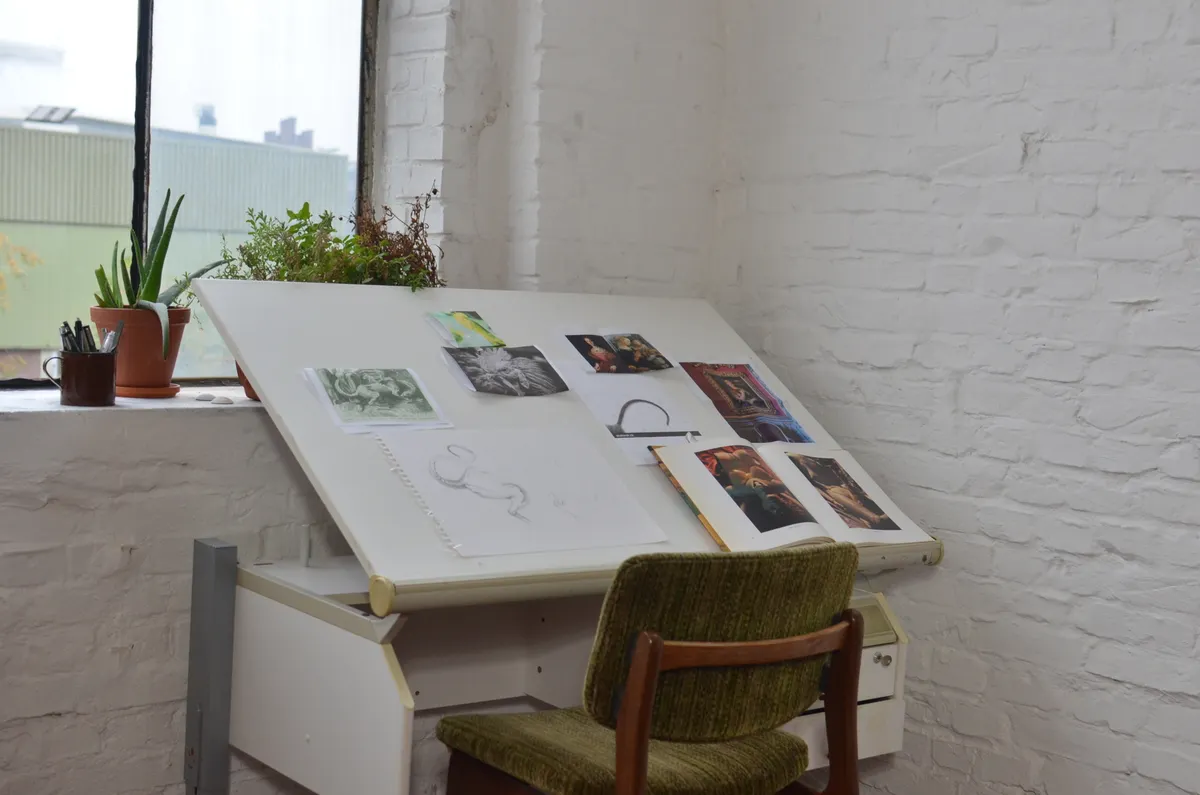 Arbeitsplatz einer Gestalterin mit Kunstwerken und Skizzen an der Wand