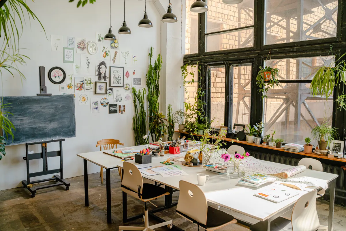 Helles Atelier mit Arbeitstischen, Pflanzen und Gestaltungsmaterial